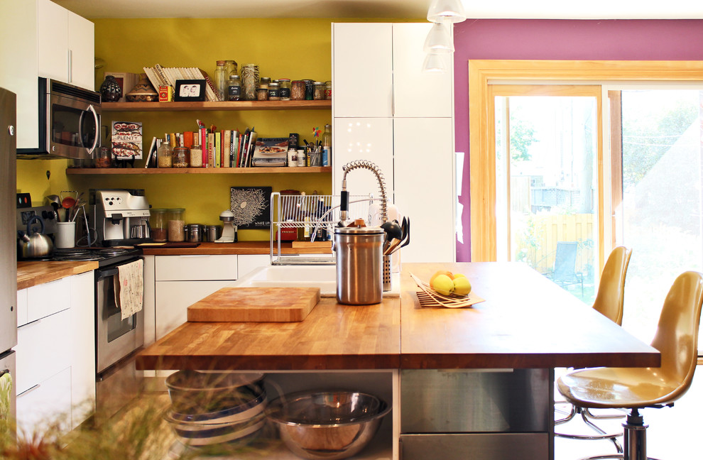 Imagen de cocina ecléctica con fregadero encastrado, armarios con paneles lisos, puertas de armario blancas, encimera de madera y electrodomésticos blancos