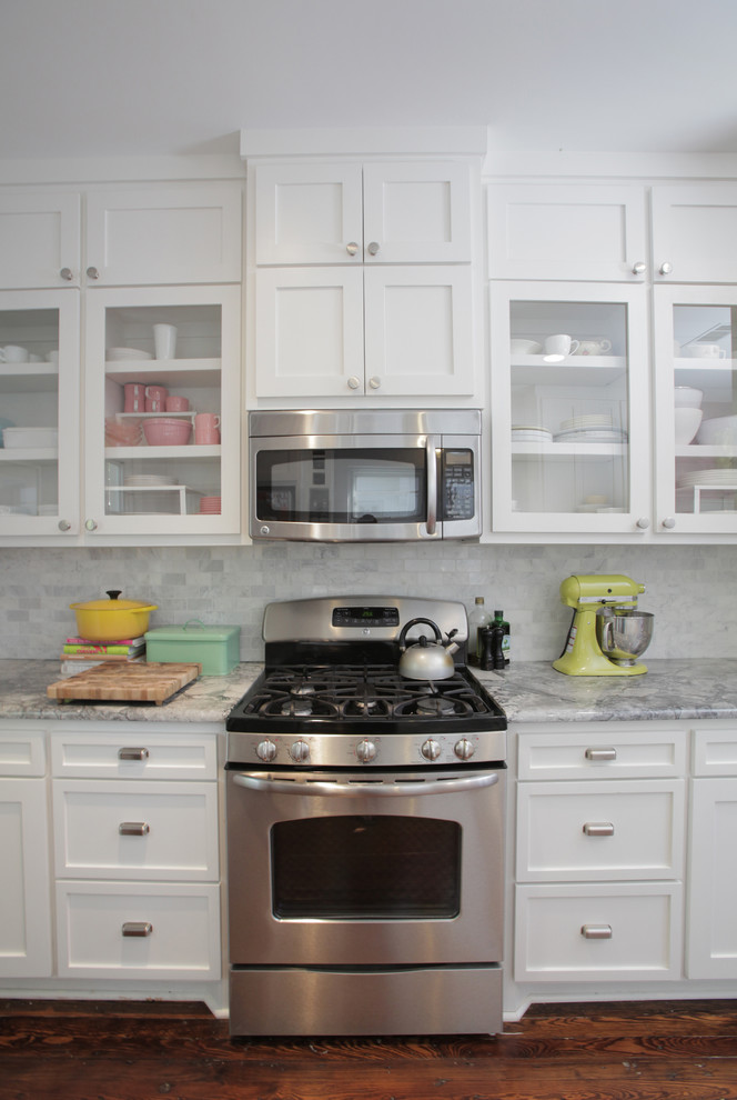 Foto de cocina ecléctica con encimera de granito, armarios estilo shaker, puertas de armario blancas, salpicadero blanco, salpicadero de azulejos de piedra y electrodomésticos de acero inoxidable