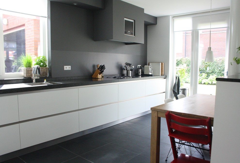 Стильный дизайн: кухня в современном стиле с плоскими фасадами, белыми фасадами и серым фартуком - последний тренд
