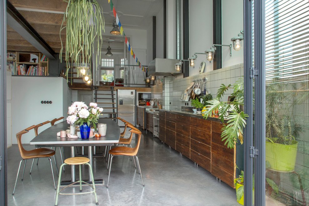 Photo of an eclectic single-wall kitchen in Other with flat-panel cabinets, dark wood cabinets, grey splashback, stainless steel appliances, concrete flooring and grey floors.