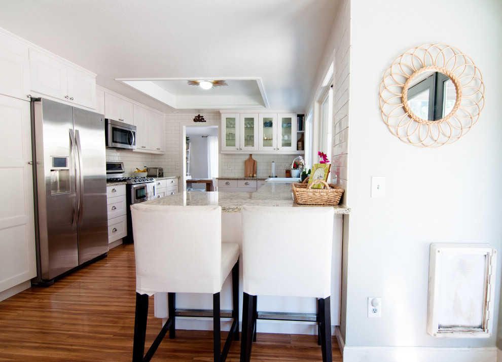 Exempel på ett mellanstort eklektiskt kök, med en rustik diskho, luckor med glaspanel, vita skåp, vitt stänkskydd, stänkskydd i tunnelbanekakel, rostfria vitvaror, en halv köksö och granitbänkskiva