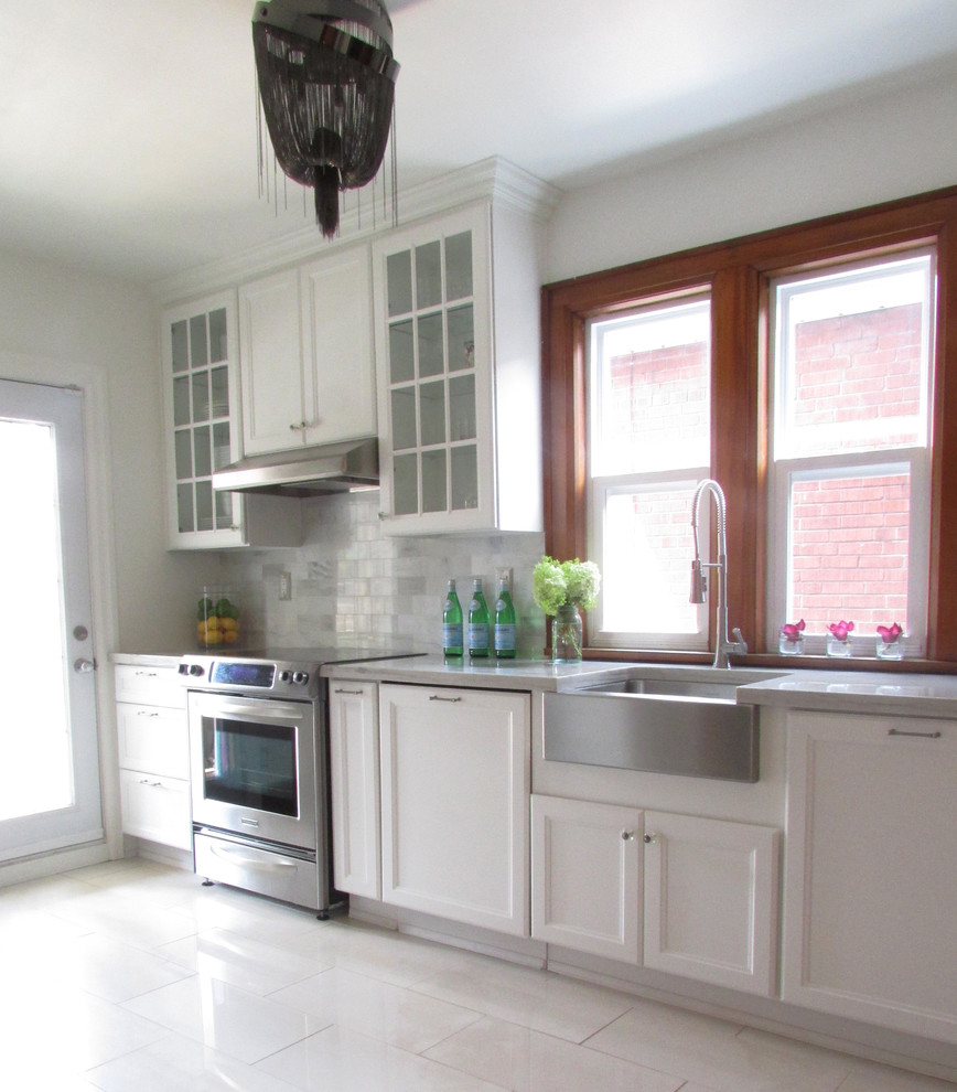 Modelo de cocina clásica con fregadero sobremueble, armarios con paneles empotrados, puertas de armario blancas, electrodomésticos de acero inoxidable y suelo blanco