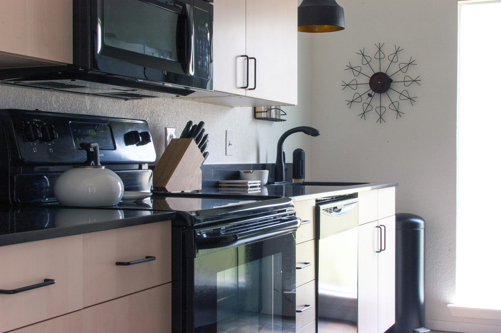 На фото: отдельная кухня в стиле ретро с плоскими фасадами, светлыми деревянными фасадами, черным фартуком и черной техникой с