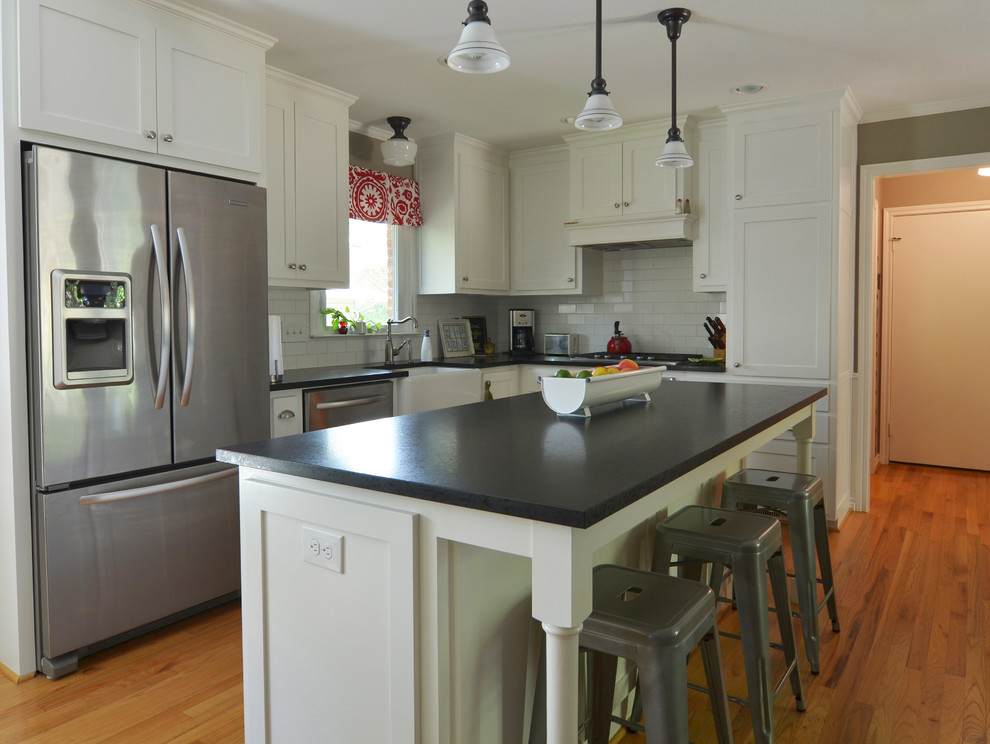 Inspiration for a timeless l-shaped eat-in kitchen remodel in Dallas with shaker cabinets, stainless steel appliances, a farmhouse sink, white cabinets, white backsplash and subway tile backsplash
