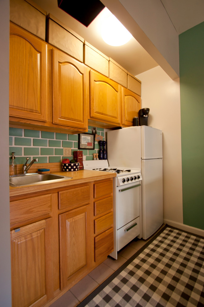 This is an example of an eclectic single-wall kitchen in New York with green splashback and white appliances.
