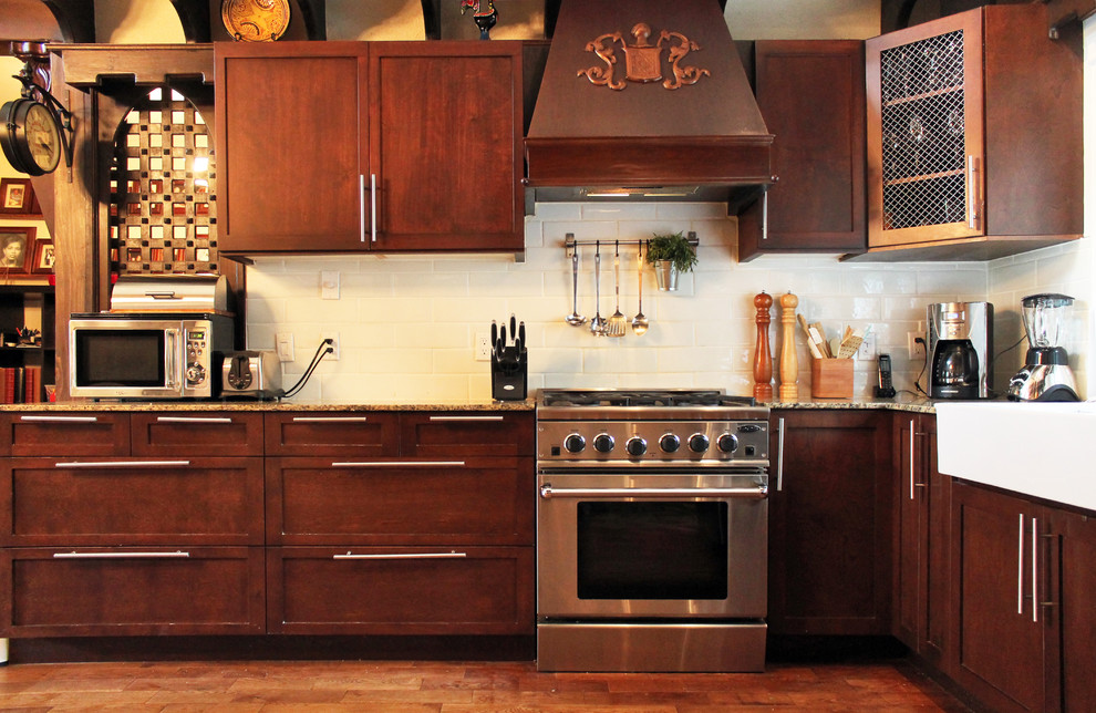 Stilmix Küche mit Landhausspüle, Schrankfronten mit vertiefter Füllung, dunklen Holzschränken, Küchenrückwand in Weiß, Rückwand aus Metrofliesen und Küchengeräten aus Edelstahl in Montreal