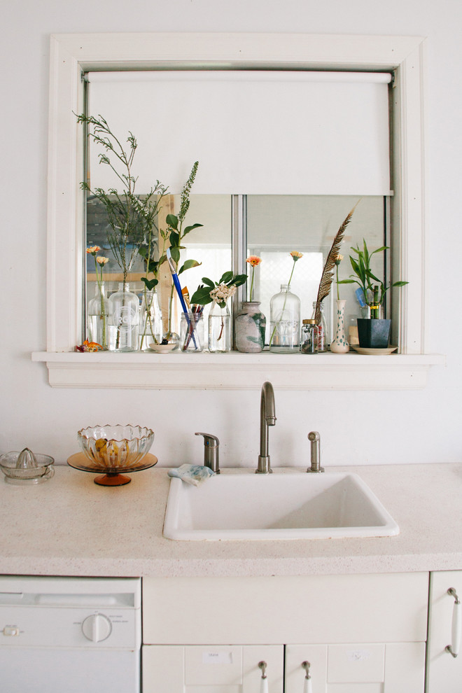 Foto på ett avskilt, mellanstort eklektiskt kök, med en enkel diskho, släta luckor, vita skåp, vita vitvaror och mellanmörkt trägolv