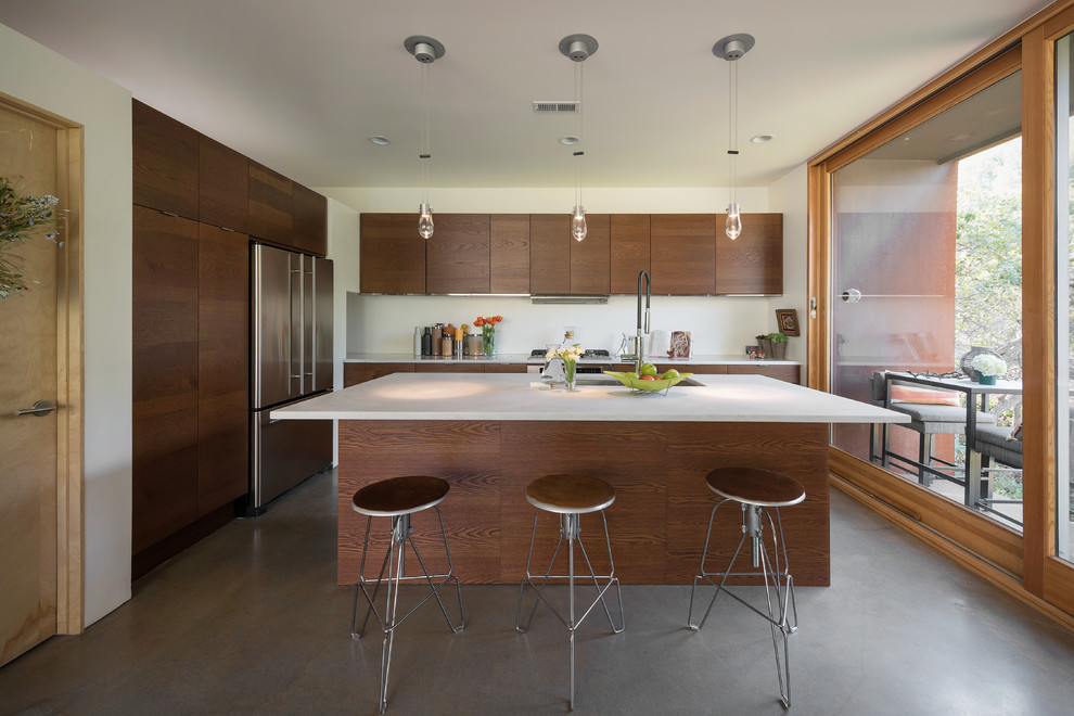Inspiration for a contemporary galley concrete floor kitchen remodel in Salt Lake City with an undermount sink, flat-panel cabinets, dark wood cabinets, stainless steel appliances and an island