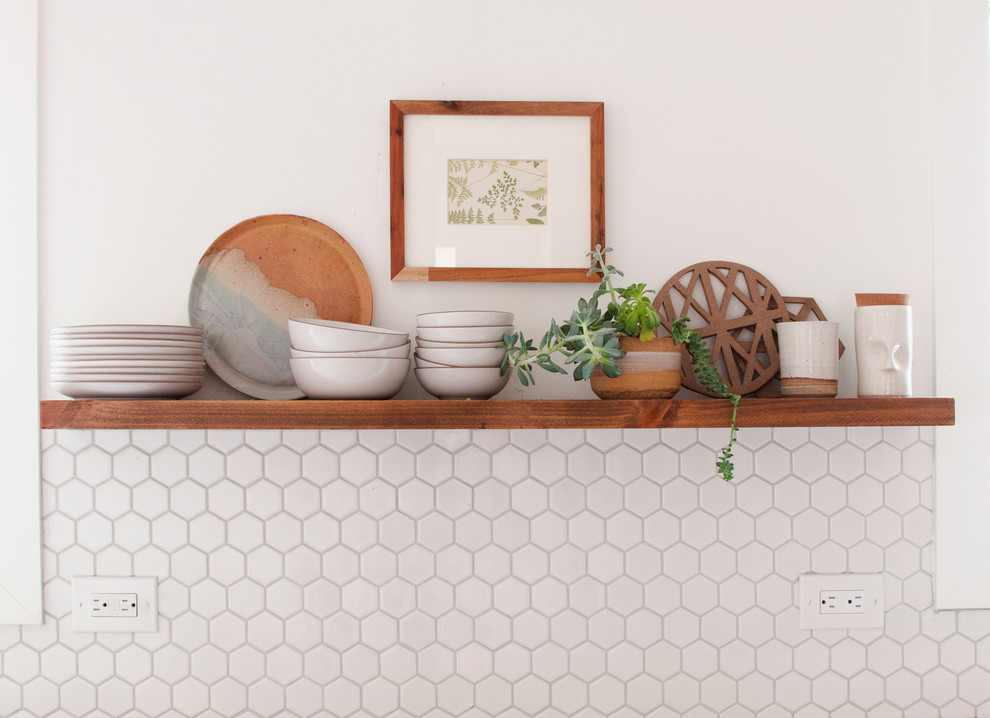 Inredning av ett retro mellanstort kök, med en enkel diskho, släta luckor, vita skåp, marmorbänkskiva, vitt stänkskydd, stänkskydd i porslinskakel, rostfria vitvaror, ljust trägolv och en halv köksö