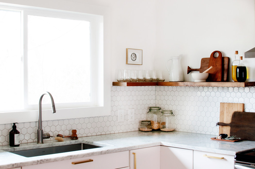 Foto på ett mellanstort retro kök, med en enkel diskho, släta luckor, vita skåp, marmorbänkskiva, vitt stänkskydd, stänkskydd i porslinskakel, rostfria vitvaror, ljust trägolv och en halv köksö