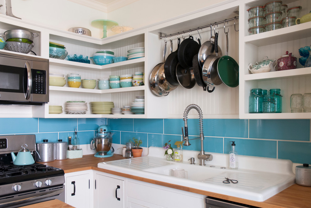 Eat-in kitchen - mid-sized eclectic l-shaped eat-in kitchen idea in Columbus with a drop-in sink, open cabinets, white cabinets, wood countertops, blue backsplash, subway tile backsplash, stainless steel appliances and an island