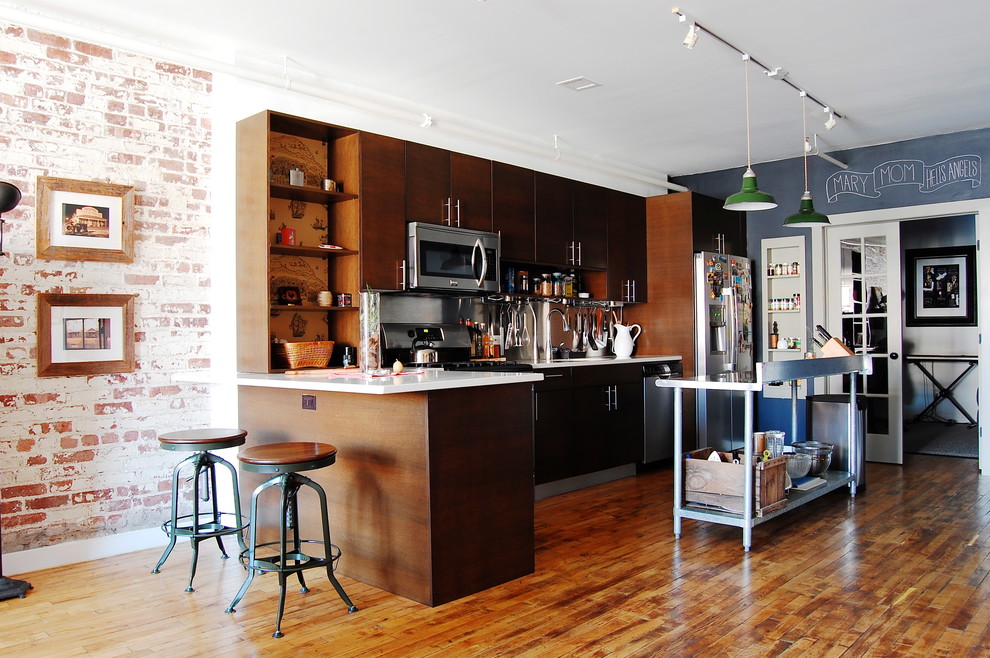 ニューヨークにあるインダストリアルスタイルのおしゃれなキッチン (フラットパネル扉のキャビネット、濃色木目調キャビネット、シルバーの調理設備) の写真