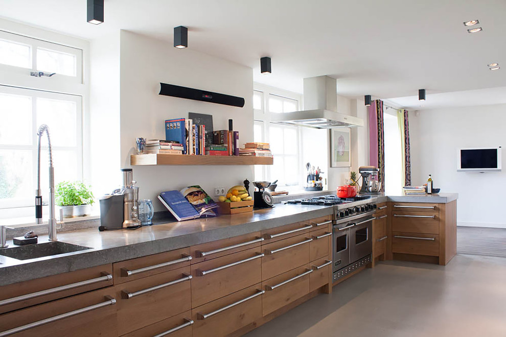 Стильный дизайн: кухня в современном стиле с монолитной мойкой, плоскими фасадами, светлыми деревянными фасадами и техникой из нержавеющей стали - последний тренд