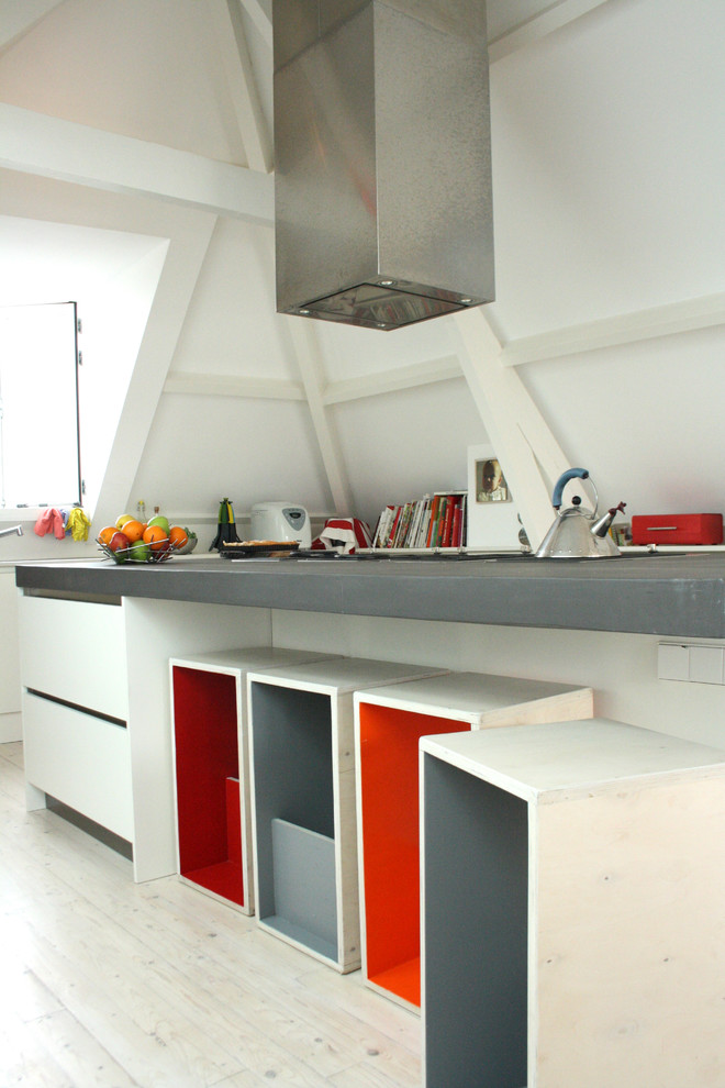 Cette photo montre une cuisine moderne avec des portes de placard blanches et un plan de travail en béton.