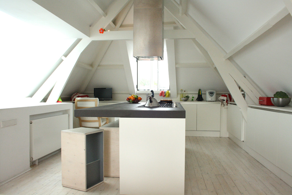 Cette image montre une cuisine minimaliste avec un placard à porte plane, des portes de placard blanches et un plan de travail en béton.