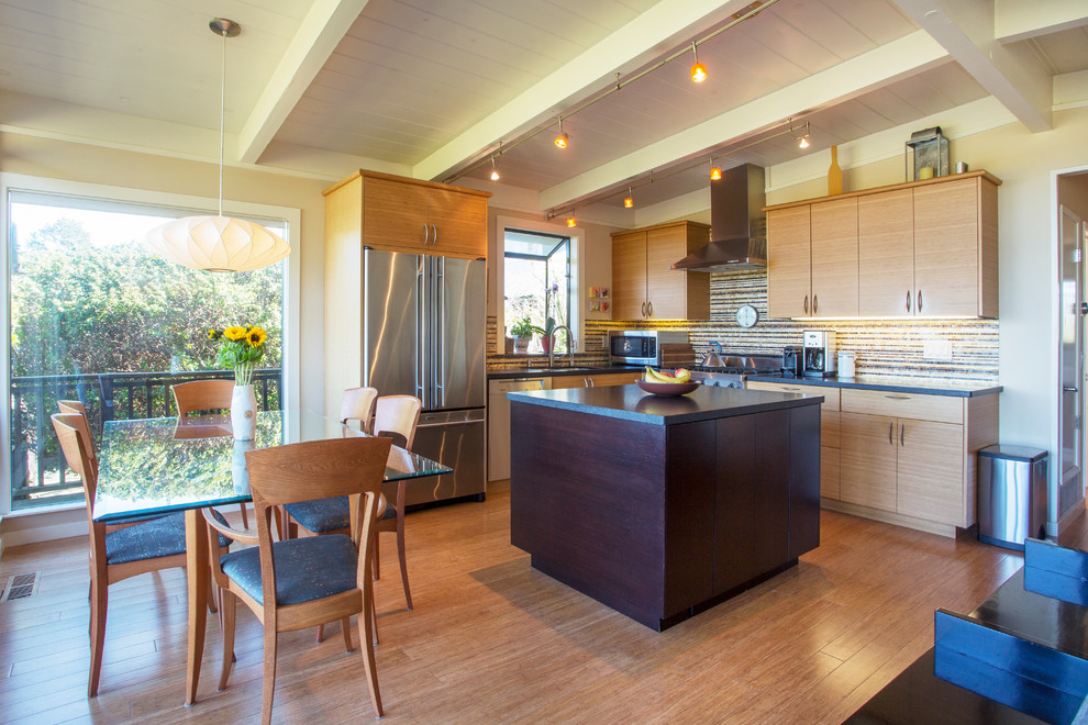 Photo of a retro l-shaped kitchen/diner in San Francisco with flat-panel cabinets, light wood cabinets, an island, a submerged sink, multi-coloured splashback, stainless steel appliances and beige floors.