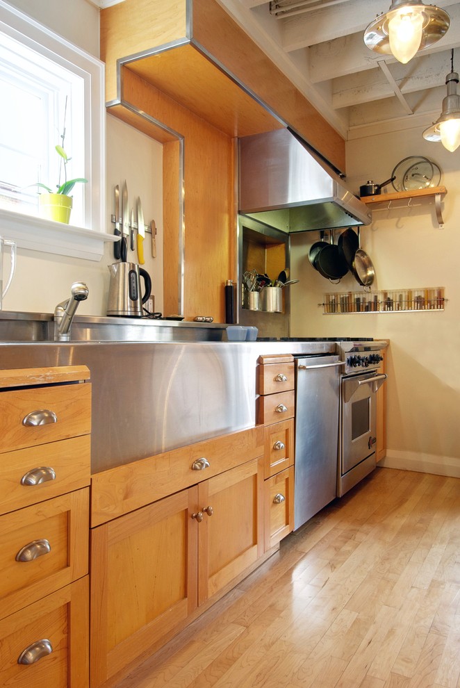トロントにあるトランジショナルスタイルのおしゃれなキッチン (一体型シンク、シルバーの調理設備、淡色木目調キャビネット、ステンレスカウンター、シェーカースタイル扉のキャビネット) の写真