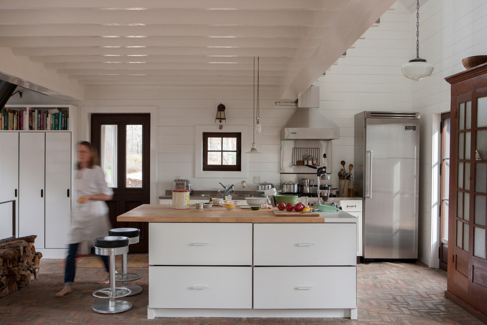 Immagine di una cucina lineare stile rurale con lavello da incasso, ante lisce, ante bianche, top in legno e elettrodomestici in acciaio inossidabile