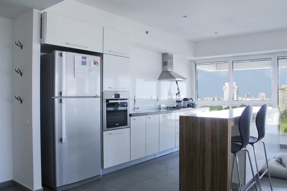 Cette photo montre une cuisine tendance avec un placard à porte plane, des portes de placard blanches et un électroménager en acier inoxydable.