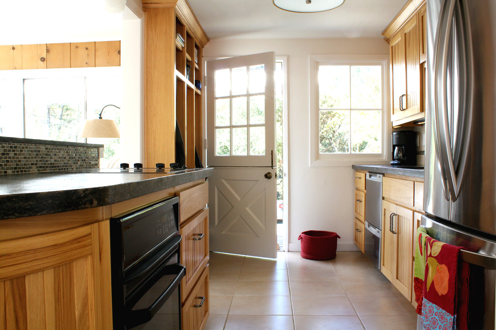 Aménagement d'une cuisine parallèle classique en bois brun fermée avec un placard avec porte à panneau encastré, un plan de travail en granite et un électroménager en acier inoxydable.