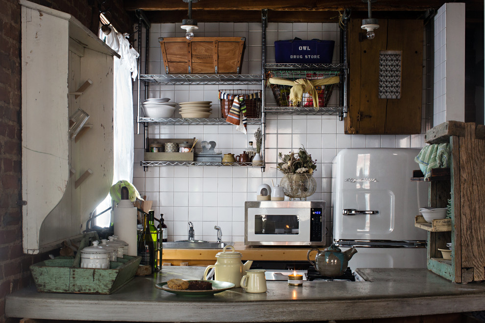 Zweizeilige Industrial Küche mit Einbauwaschbecken, offenen Schränken, Küchenrückwand in Weiß, weißen Elektrogeräten, Halbinsel und grauer Arbeitsplatte