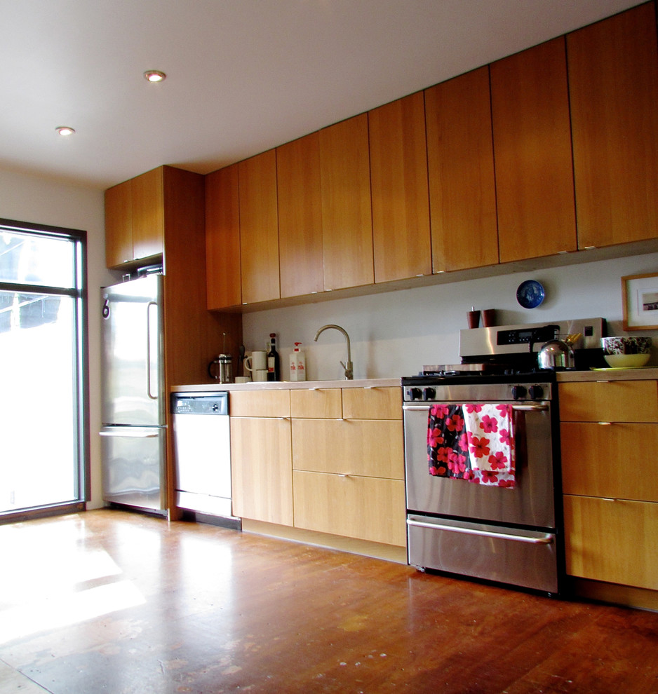 トロントにあるコンテンポラリースタイルのおしゃれなI型キッチン (フラットパネル扉のキャビネット、中間色木目調キャビネット、シルバーの調理設備) の写真