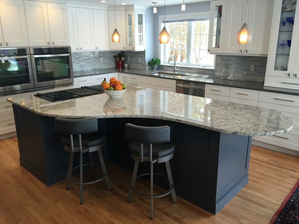 Mid-sized elegant l-shaped light wood floor eat-in kitchen photo in Boston with a single-bowl sink, recessed-panel cabinets, white cabinets, granite countertops, gray backsplash, ceramic backsplash, stainless steel appliances and an island