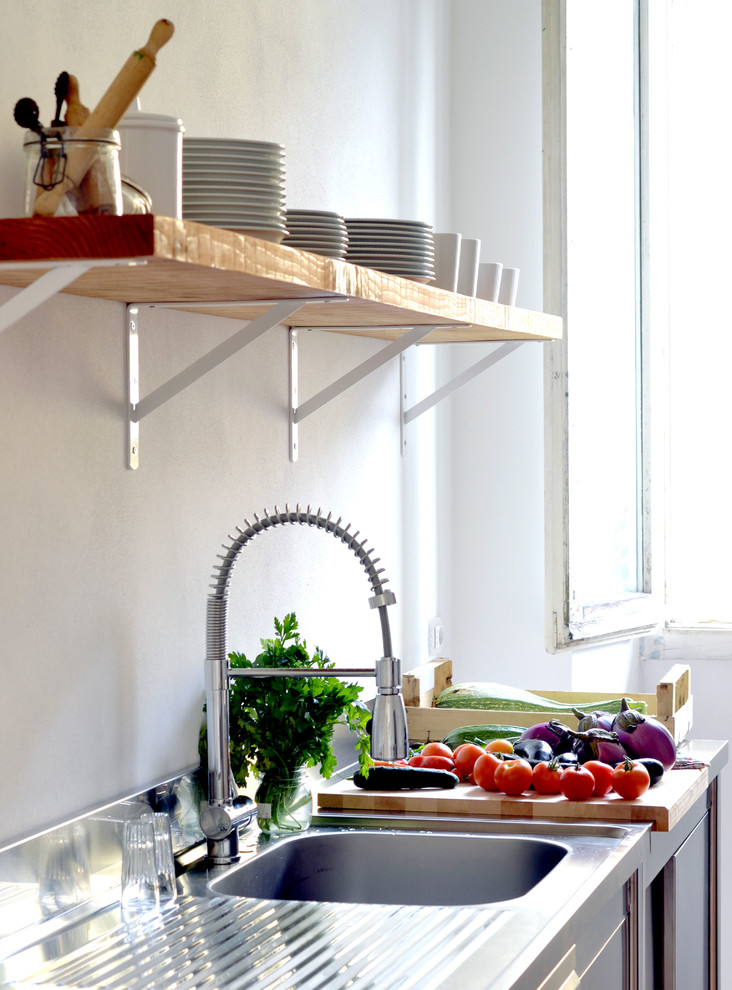 Foto di una cucina industriale con lavello a vasca singola, nessun'anta, ante in legno scuro, top in acciaio inossidabile e paraspruzzi bianco