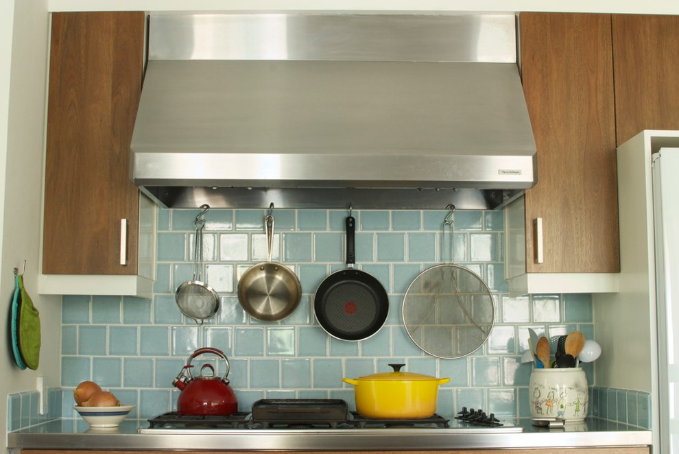 他の地域にあるコンテンポラリースタイルのおしゃれなキッチン (青いキッチンパネル、中間色木目調キャビネット、フラットパネル扉のキャビネット) の写真