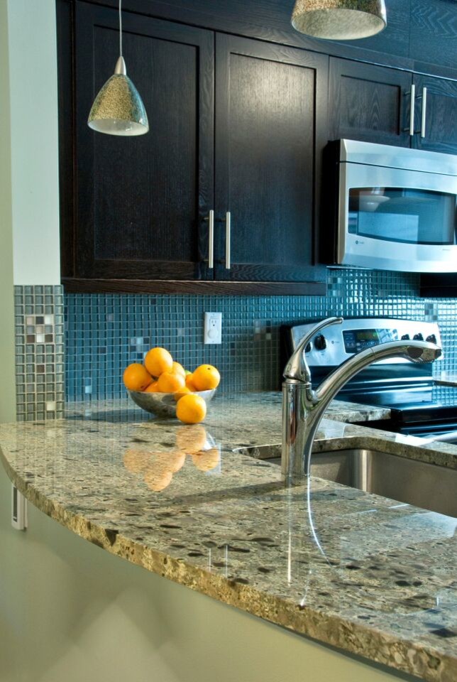 Klassisk inredning av ett kök, med en undermonterad diskho, skåp i shakerstil, svarta skåp, granitbänkskiva, flerfärgad stänkskydd, stänkskydd i glaskakel och rostfria vitvaror