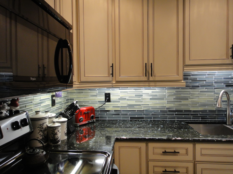 Klassische Wohnküche in L-Form mit Unterbauwaschbecken, Schrankfronten im Shaker-Stil, beigen Schränken, Granit-Arbeitsplatte, Küchenrückwand in Grün und schwarzen Elektrogeräten in Toronto