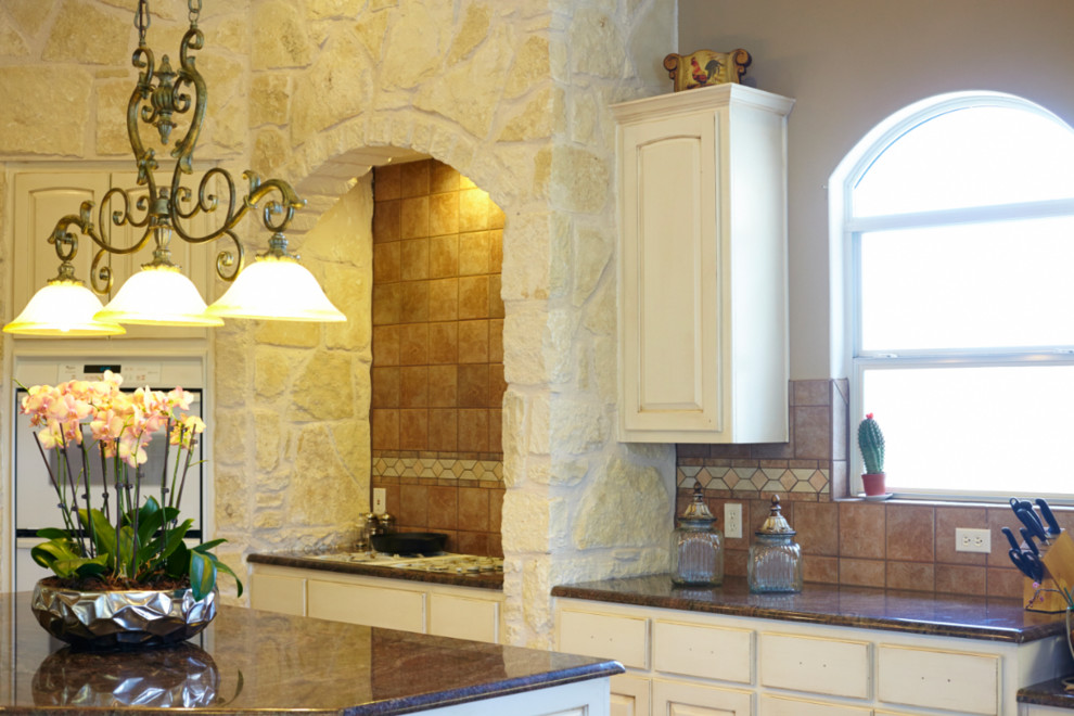 Foto di una cucina tradizionale di medie dimensioni con ante con bugna sagomata, ante bianche, top in granito, paraspruzzi arancione, paraspruzzi in gres porcellanato e elettrodomestici bianchi
