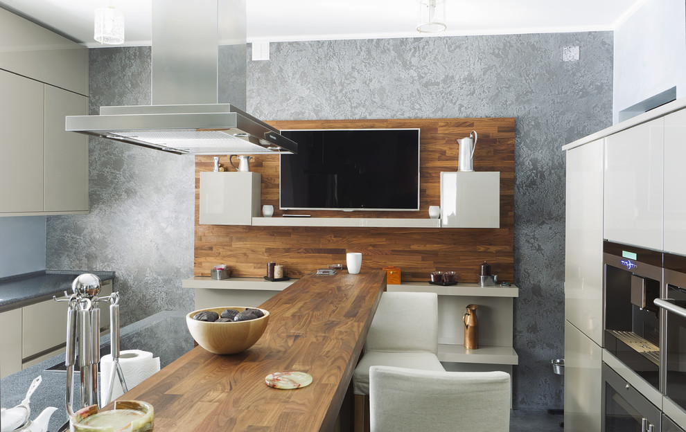 Cette photo montre une cuisine parallèle moderne de taille moyenne avec un placard à porte plane, des portes de placard beiges, un plan de travail en bois, une crédence bleue, un électroménager en acier inoxydable et îlot.