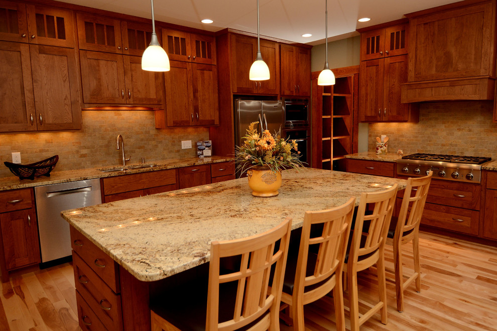 Exempel på ett mellanstort klassiskt kök, med en undermonterad diskho, luckor med infälld panel, skåp i mellenmörkt trä, granitbänkskiva, beige stänkskydd, stänkskydd i stenkakel, rostfria vitvaror, ljust trägolv och en köksö