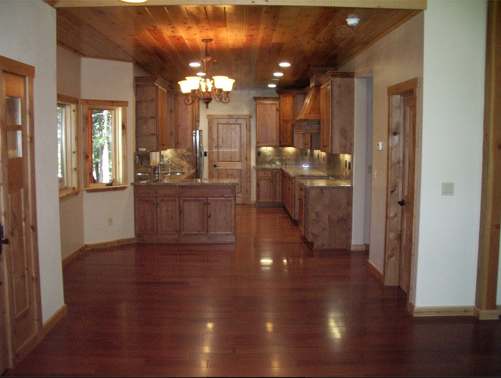 Klassisk inredning av ett litet linjärt kök med öppen planlösning, med luckor med infälld panel, skåp i mellenmörkt trä, rostfria vitvaror och mellanmörkt trägolv