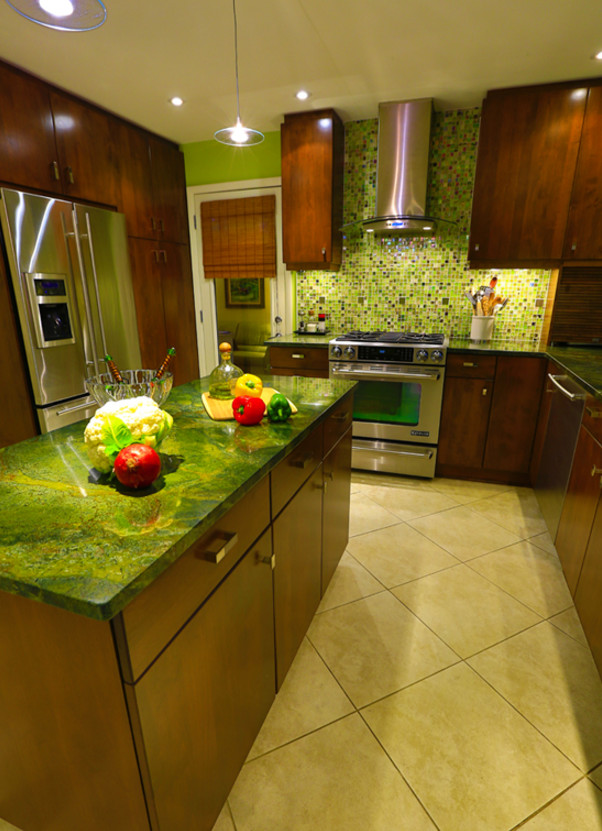 Photo of a medium sized eclectic u-shaped kitchen in Other with a submerged sink, flat-panel cabinets, medium wood cabinets, green splashback, glass tiled splashback, stainless steel appliances, ceramic flooring, an island, beige floors and green worktops.