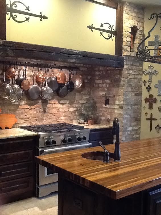 Bild på ett vintage kök, med en enkel diskho, träbänkskiva, stänkskydd i tegel, rostfria vitvaror, en köksö, luckor med upphöjd panel, skåp i mörkt trä, brunt stänkskydd och cementgolv
