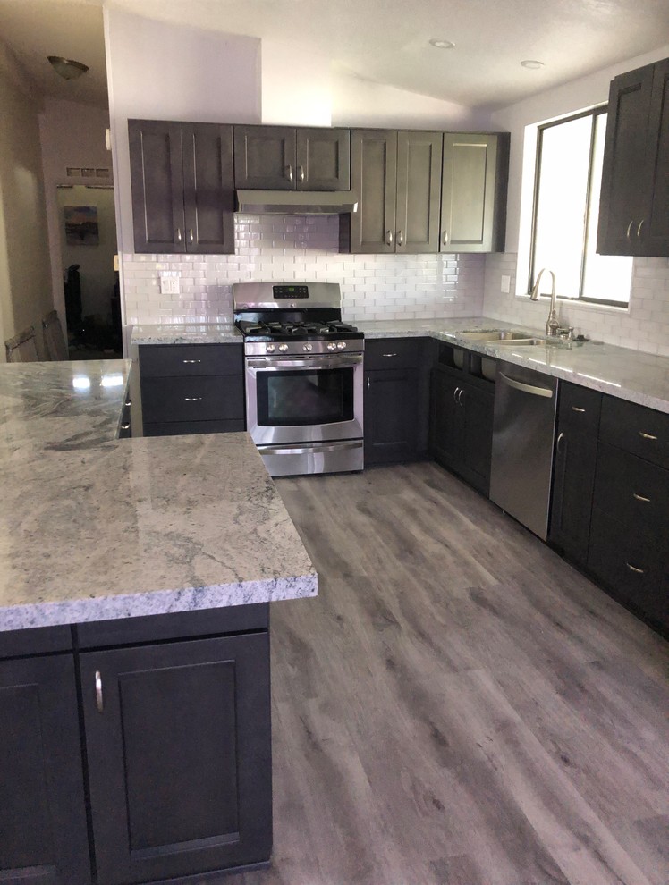 This is an example of a medium sized classic l-shaped kitchen/diner in San Diego with shaker cabinets, grey cabinets, engineered stone countertops, glass tiled splashback, stainless steel appliances, vinyl flooring, an island, grey floors, grey worktops, a submerged sink and white splashback.