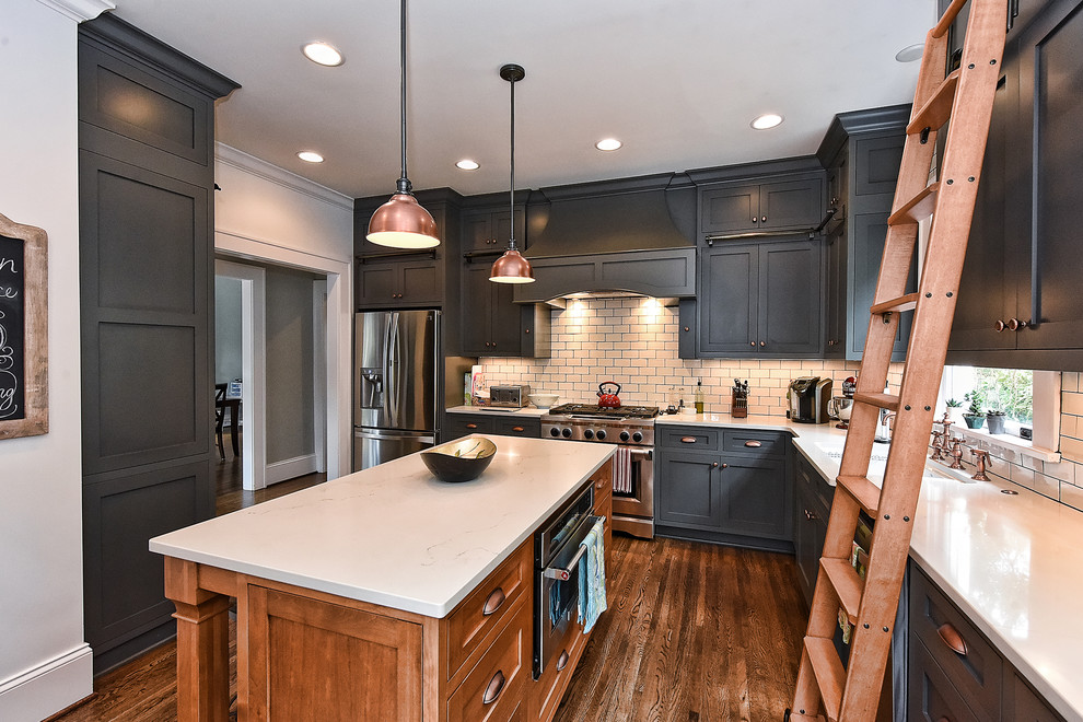 Example of a country l-shaped medium tone wood floor enclosed kitchen design in Charlotte with a single-bowl sink, shaker cabinets, gray cabinets, marble countertops, white backsplash, subway tile backsplash, stainless steel appliances and an island