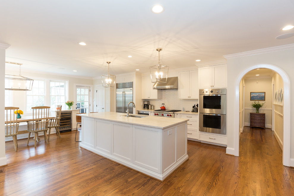 Huge transitional single-wall medium tone wood floor and brown floor eat-in kitchen photo in Charlotte with an undermount sink, recessed-panel cabinets, white cabinets, quartzite countertops, white backsplash, subway tile backsplash, stainless steel appliances and an island