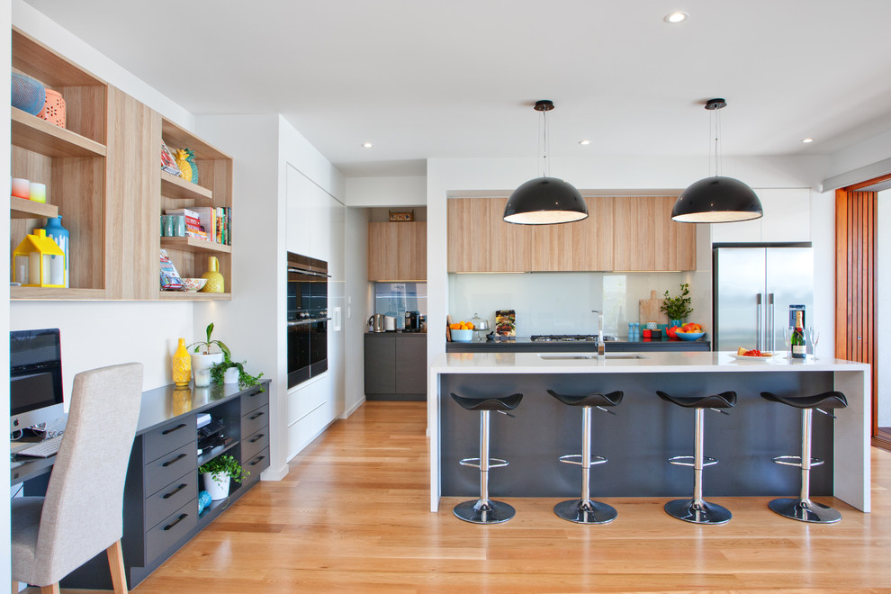 Moderne Küche mit schwarzen Schränken, Quarzwerkstein-Arbeitsplatte, Glasrückwand und Kücheninsel in Sunshine Coast
