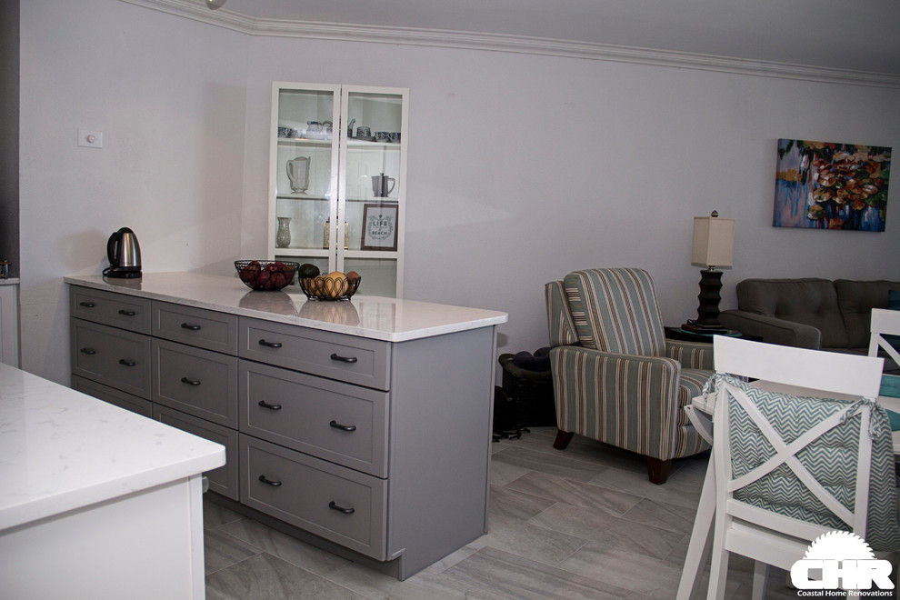 Photo of a beach style kitchen in Other with a submerged sink, shaker cabinets, white cabinets, marble worktops, white splashback, ceramic splashback, stainless steel appliances and light hardwood flooring.