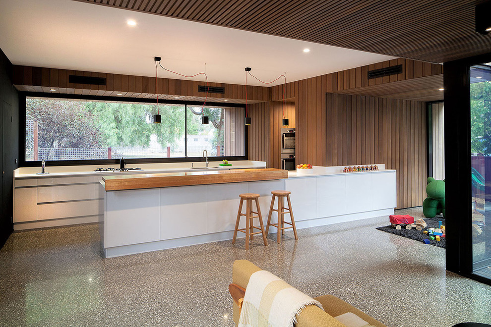 Kitchen - mid-sized contemporary galley kitchen idea in Melbourne with a double-bowl sink, flat-panel cabinets, white cabinets and stainless steel appliances