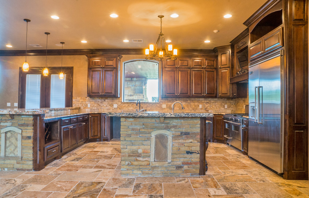 Photo of a large traditional u-shaped kitchen/diner in Oklahoma City with a built-in sink, recessed-panel cabinets, dark wood cabinets, granite worktops, beige splashback, stone tiled splashback, stainless steel appliances, slate flooring and an island.