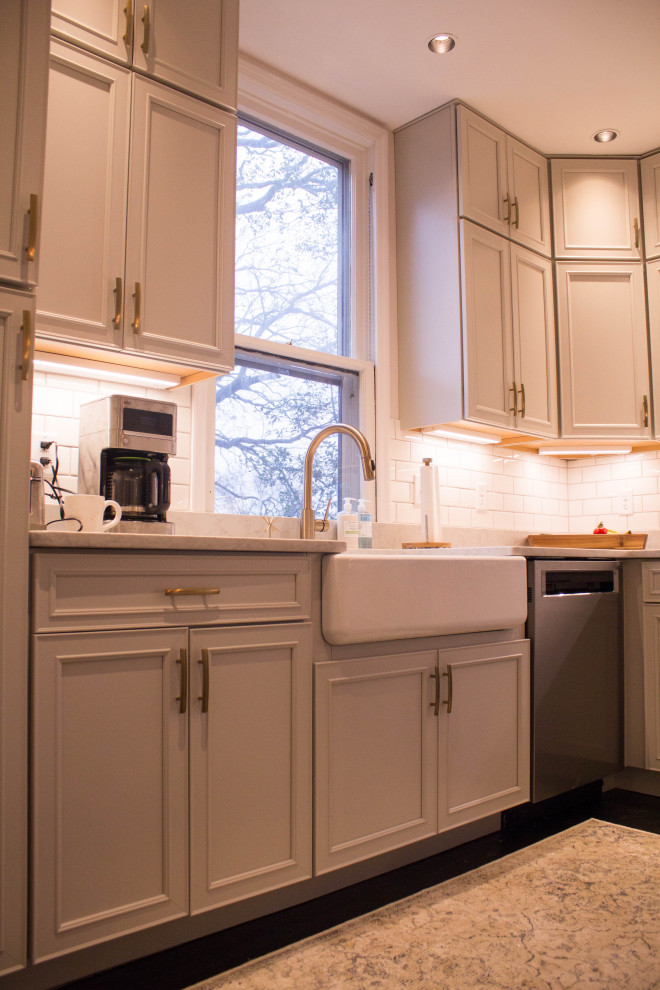 セントルイスにある高級な広いシャビーシック調のおしゃれなキッチン (エプロンフロントシンク、フラットパネル扉のキャビネット、グレーのキャビネット、クオーツストーンカウンター、白いキッチンパネル、サブウェイタイルのキッチンパネル、シルバーの調理設備、濃色無垢フローリング、黒い床、白いキッチンカウンター) の写真