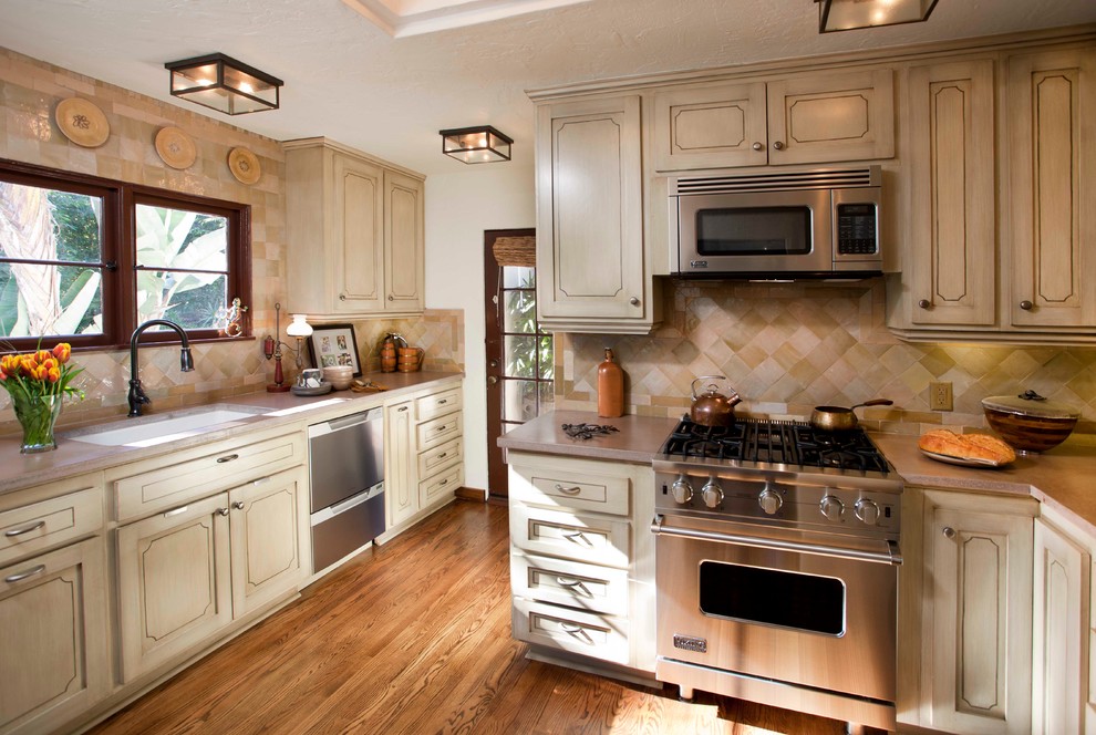 サンディエゴにある地中海スタイルのおしゃれな独立型キッチン (アンダーカウンターシンク、落し込みパネル扉のキャビネット、ベージュのキャビネット、ベージュキッチンパネル、シルバーの調理設備) の写真