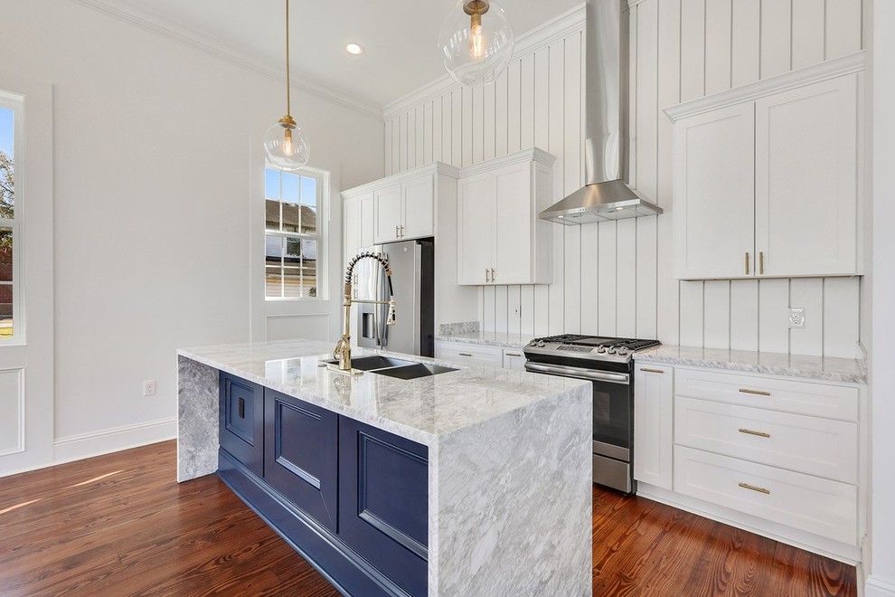 Example of a mid-sized trendy single-wall medium tone wood floor and brown floor kitchen design in New Orleans with an undermount sink, shaker cabinets, white cabinets, quartzite countertops, white backsplash, wood backsplash, stainless steel appliances, an island and white countertops