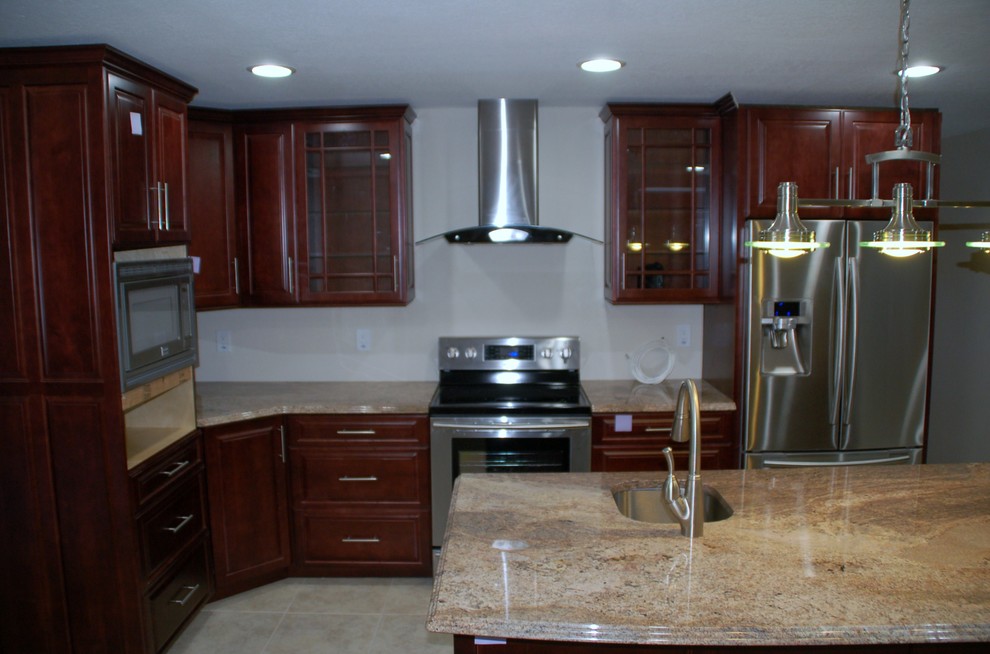 Foto på ett mellanstort vintage kök, med luckor med upphöjd panel, skåp i mellenmörkt trä, granitbänkskiva, vitt stänkskydd, rostfria vitvaror, klinkergolv i porslin och en köksö