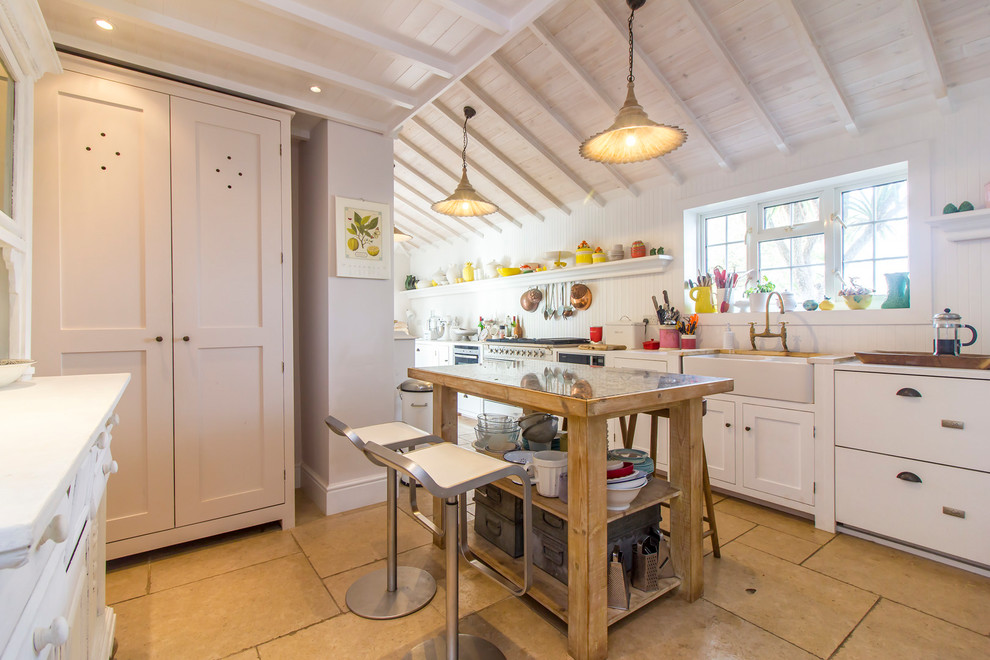 Inspiration for a mid-sized cottage single-wall beige floor kitchen remodel in Kent with a farmhouse sink, recessed-panel cabinets, white cabinets, wood countertops and an island