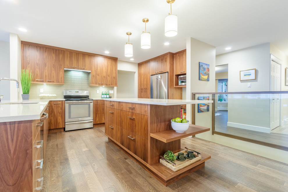 Contemporary kitchen/diner in Vancouver with a submerged sink, flat-panel cabinets, medium wood cabinets, glass tiled splashback, stainless steel appliances, medium hardwood flooring, multiple islands, brown floors and white worktops.